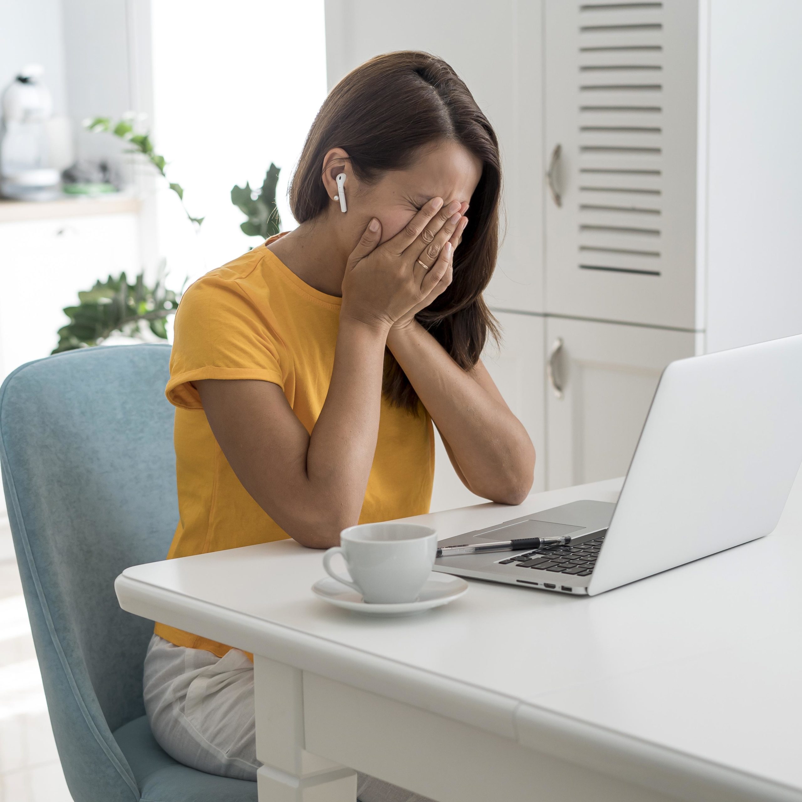 Kobieta siedzi przed komputerem i zasłania rękami twarz. Jak pisać teksty do internetu, by nie uśpić czytelnika?