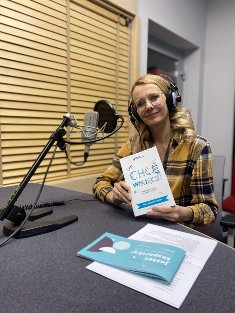 Kasia Zubrzycka-Sarna w słuchawkach przed mikrofonem, studio Radia Plus, książka Chcę WWWięcej